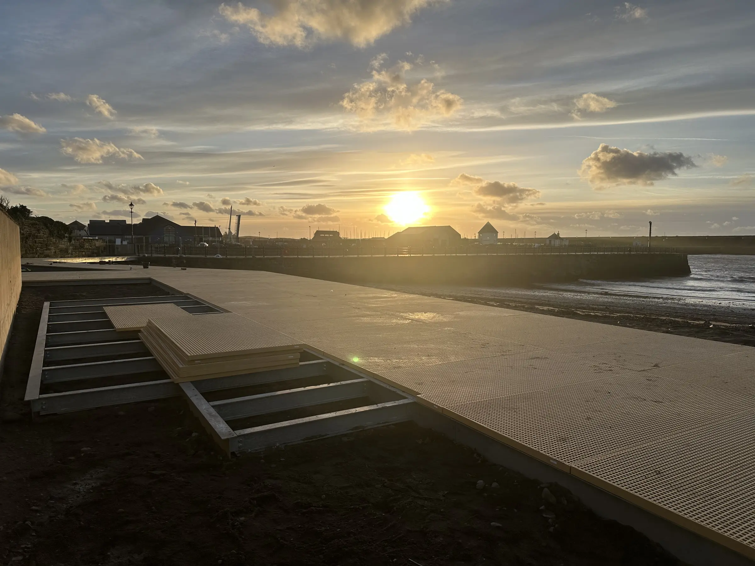 Maryport Boardwalk structure extending across the beach toward the harbour in evening coastal light