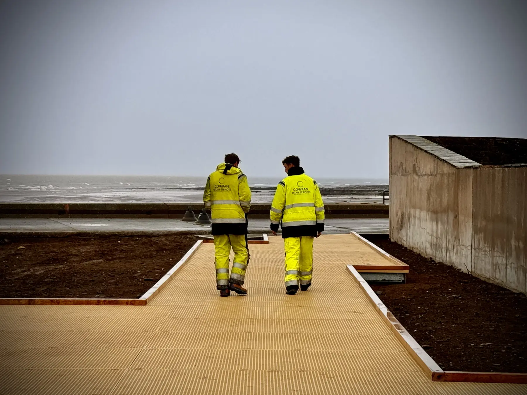 Cowran Estate Services team walking the Maryport Boardwalk during final-phase work in the marine environment